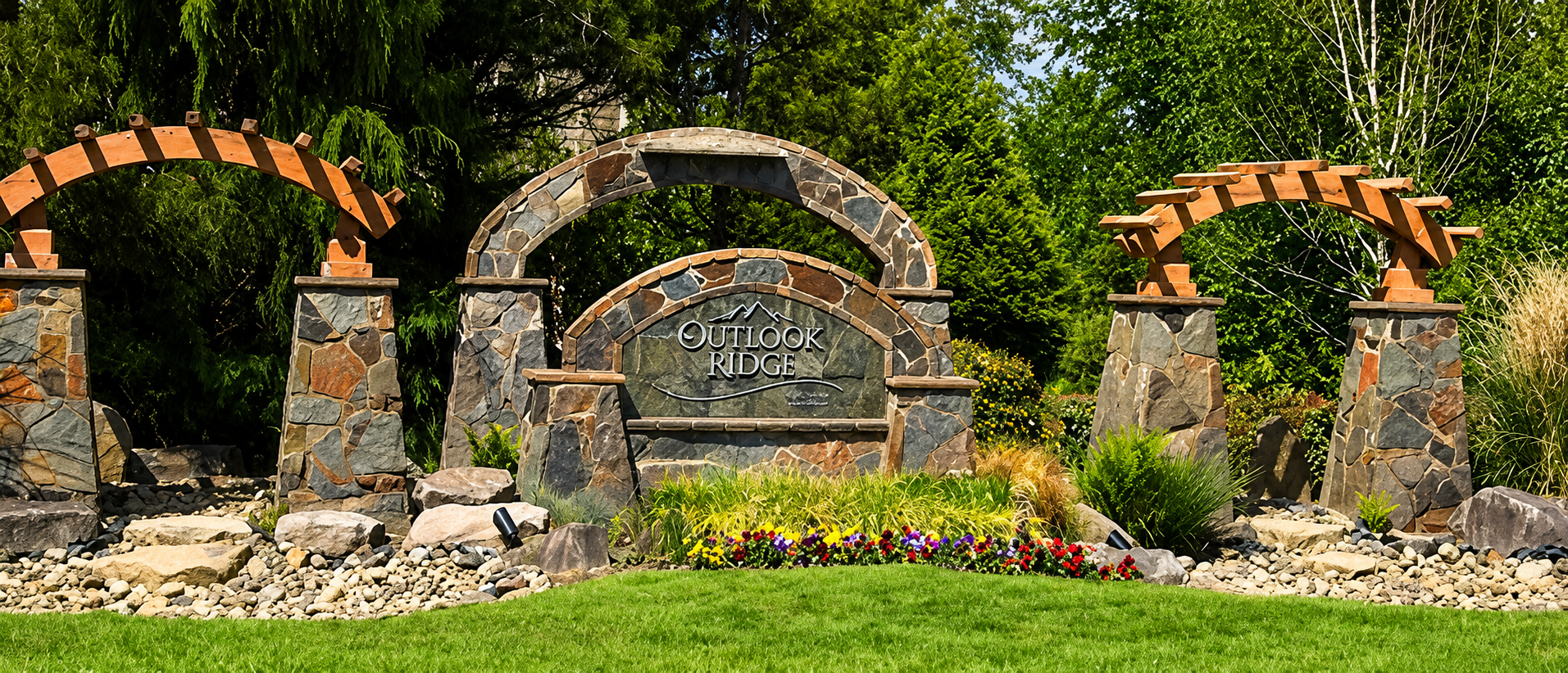 Stone entrance sign with arches and landscaping.