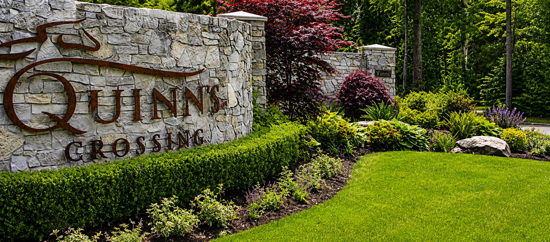 Stone entrance sign with landscaped greenery.